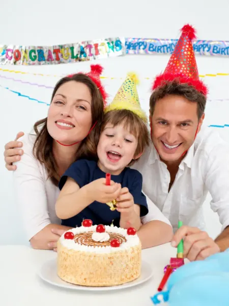 Familia con gorros de fiesta y torta de cumpleaños